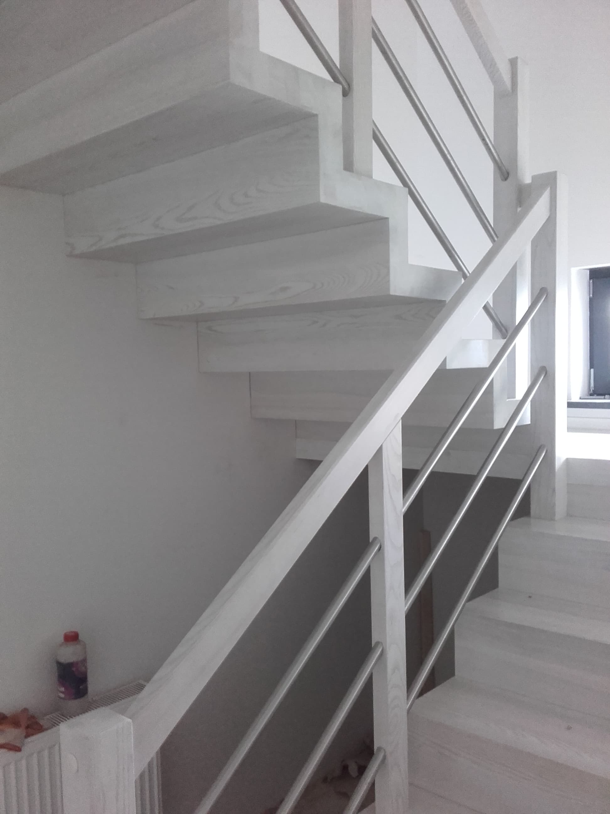 Białe schody drewniane z nowoczesną metalową balustradą i minimalistycznym designem